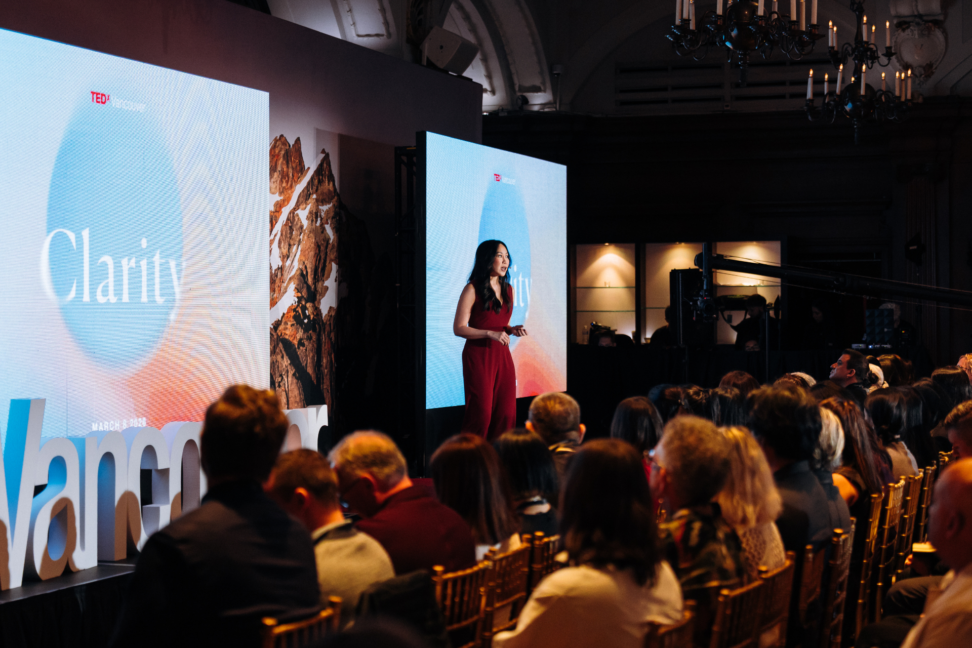 Amy Chan speaking on stage in a red dress at a live event